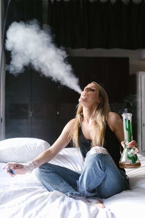 woman using bong on bed